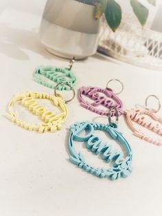 four different colored earrings sitting on top of a white table next to a potted plant