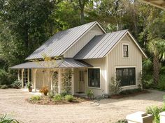 a white house with a metal roof surrounded by trees