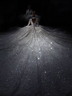 a woman laying on top of a bed covered in white sheets and sparkles at night