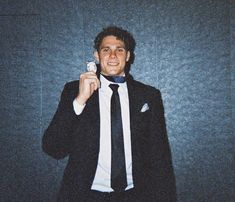 a man in a suit and tie holding up a small object