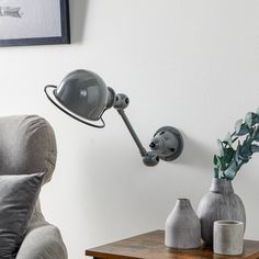 a lamp that is on the side of a wall next to vases and a chair