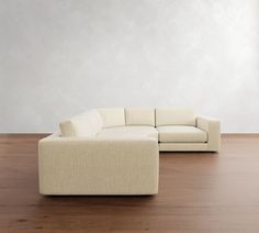 a large white couch sitting on top of a wooden floor next to a tall wall