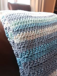 a crocheted blanket sitting on top of a brown chair