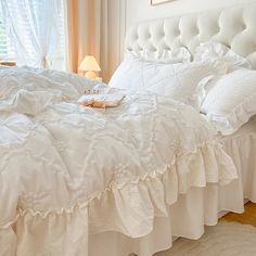 a bed with white ruffled bedspread and pillows