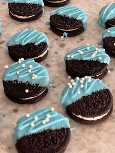 cookies with blue frosting and white sprinkles are arranged on a table