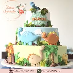 a three tiered cake decorated with dinosaurs and plants