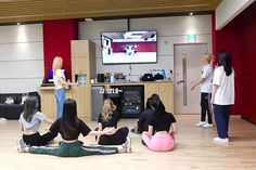 group of people sitting on the floor in front of a flat screen tv playing an interactive video game