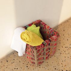 a basket with towels and a yellow towel on the floor next to a white wall