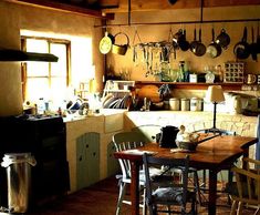 an old fashioned kitchen with pots and pans hanging on the wall above the stove