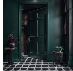 a green door in a dark room with black and white floor tiles on the floor