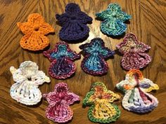 six crocheted angel ornaments on a wooden table