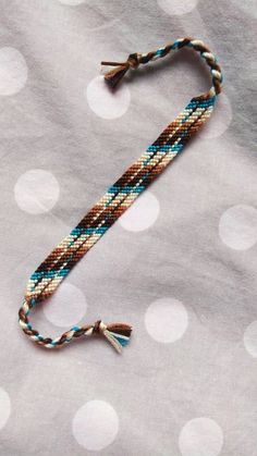 a blue and brown beaded bracelet with tassels sitting on top of a table