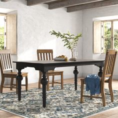 a dining room table with chairs and a rug in front of the table is shown