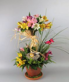 a potted plant filled with lots of different flowers on top of a white surface