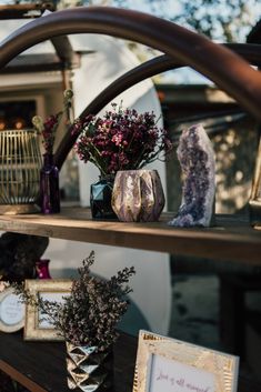 some vases with flowers are sitting on a shelf next to pictures and other items