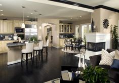 a large open concept kitchen and living room with wood floors, white furniture and black accents