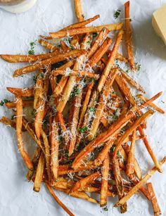 french fries with parmesan cheese and herbs on white paper next to sliced cheese