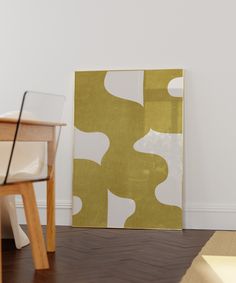 a white chair sitting in front of a painting on the wall next to a wooden table