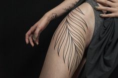 a woman's leg with a feather tattoo on her left arm and the lower half of her leg