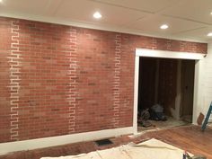 an unfinished room with brick walls and wood flooring being worked on by the workers