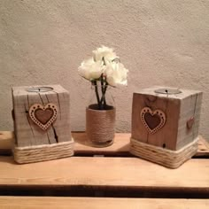 three wooden boxes with hearts and flowers in them on a table next to a wall