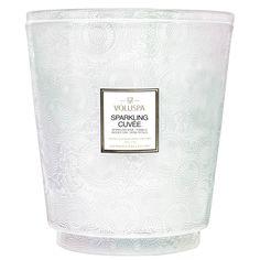 a candle that is white and has a black label on the front, with an ornate pattern