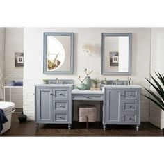 a bathroom vanity with two mirrors above it and a bathtub in the back ground