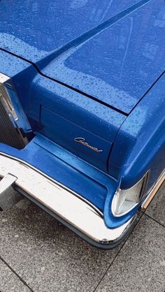 the front end of an old blue car with it's hood up and door open