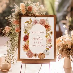 a welcome sign sitting on top of a table next to vases with flowers in them