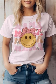 a woman wearing a t - shirt with a smiley face on the front and pink bows in her hair