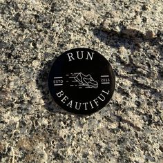 a black and white button that says run beautiful on the side of a stone wall