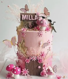 there is a pink cake with flowers and butterflies on the top, surrounded by other decorations