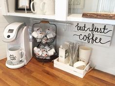 a coffee maker sitting on top of a wooden counter next to cups and mugs