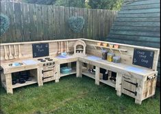 an outdoor kitchen made out of pallet wood with chalkboard on the back wall