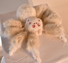 a stuffed animal laying on top of a white tablecloth covered bed with red eyes