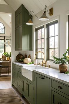 a kitchen filled with lots of green cabinets and white counter tops next to a window