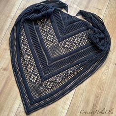 a black crocheted shawl on a wooden floor