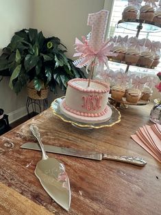 a table topped with a cake and cupcakes on top of it next to a spatula