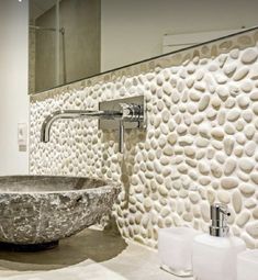 a bathroom with a stone bowl sink and soap dispenser