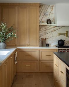 a kitchen with wooden cabinets and marble counter tops, along with a vase filled with flowers