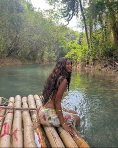 a woman is sitting on bamboo raft in the water