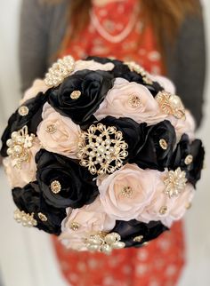 a bridal bouquet in black, pink and gold with brooches on it