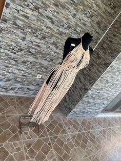 a black and white dress hanging from the ceiling in a room with stone flooring