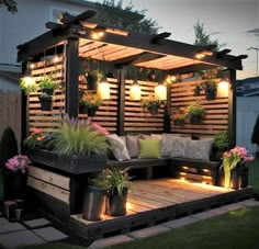 an outdoor seating area is lit up with lights and potted plants on the deck