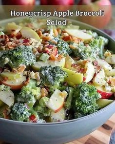 a close up of a bowl of food with broccoli and apples in the background