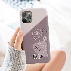 a woman is holding up her phone case with flowers on the front and back side