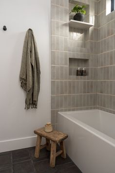 a white bath tub sitting next to a wooden bench