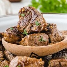 a wooden spoon filled with meat and vegetables