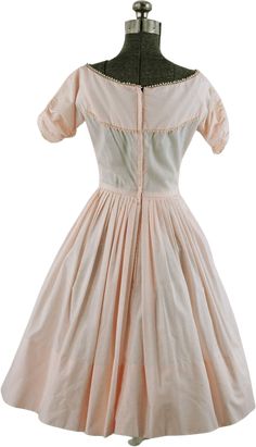 Sweet 1950s dress in alight pink, with delicate tatted trim around the neck, yoke and sleeve ends. Tiny pearly white buttons grace to bodice. The dolman sleeves are ruched, creating gathers. The long paneled waist is totally covered in narrow pin tuck pleats in front which leads to a knife-pleated full skirt. There is a deep, 7" hem. Fabric feels like a cotton blend. Metal zipper up the back. Good condition but there is light yellowing under the arms and it is missing a belt. By Tailored Junior. Measurements - Bust - 34"Waist - 24"Length - 14. 5" shoulder to waist, 39" shoulder to hem***Please note that sizes listed in the title, such as S, M or L, are estimates based on the measurements of the garment and used for search purposes. Please take note of the actual measurements and compare wi Vintage Pleated Dresses With Fitted Bodice, Feminine Fitted Victorian Daywear Dress, Feminine Fitted Victorian Dress For Daywear, Fitted Feminine Victorian Dress For Daywear, Fitted Daywear Dresses With Peter Pan Collar, Fitted Dresses With Peter Pan Collar For Daywear, Vintage Short Sleeve Dress With Fitted Bodice For Daywear, 1950s Style Daywear Dresses With Buttons, Fitted Vintage Dress With Peter Pan Collar For Daywear