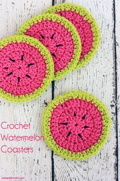 three crocheted watermelon coasters sitting on top of a wooden table